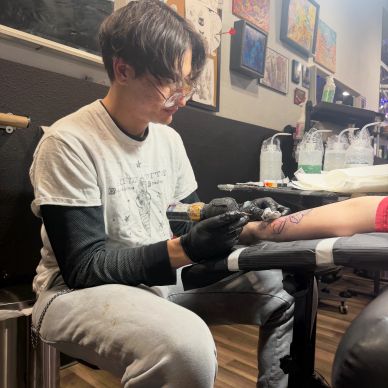 Tattoo artist focused on inking a client's arm in a cozy studio.