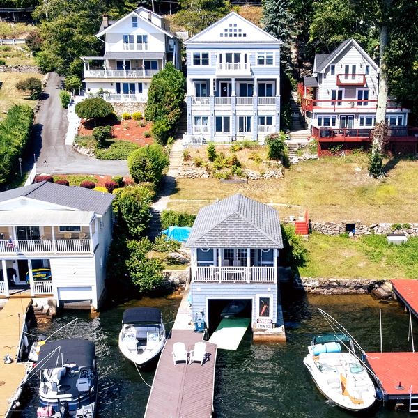 Lakefront houses with docks and boats on a sunny day.