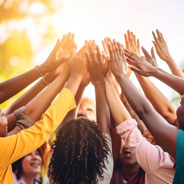 Diverse group of people joining hands together in celebration outdoors.