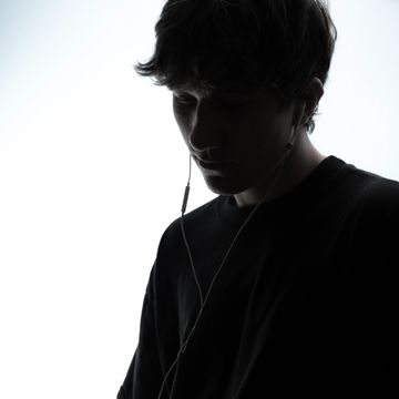 Silhouetted young man listening to music with earphones.