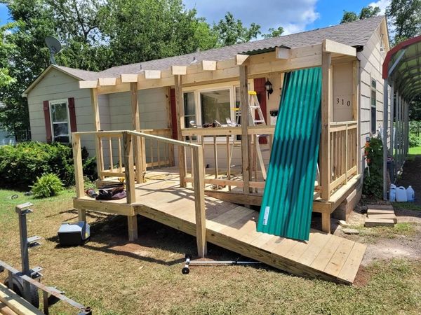 Metal roof leaned against newly built porch with wheelchair ramp. 