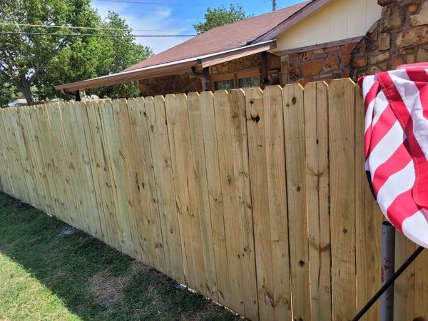 Custom-built wooden privacy fence with American flag draped over. 