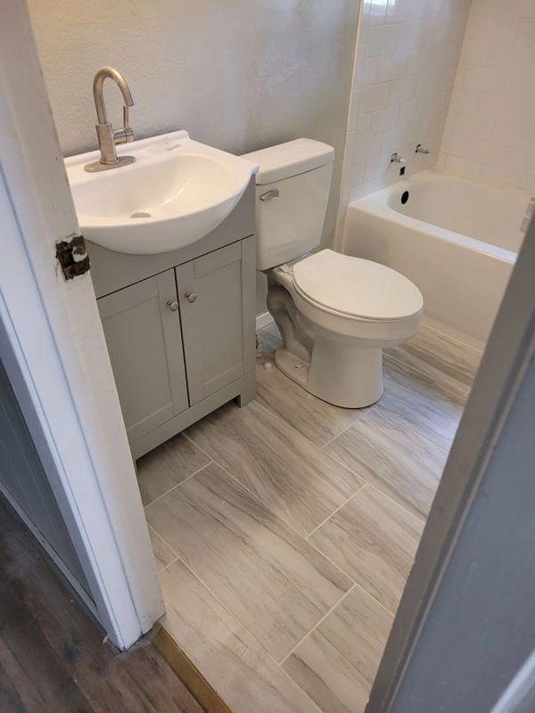 White and grey bathroom renovation, new toilet, tub, and vanity. 