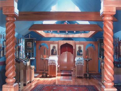 Photo of a Russian Orthodox Monastery's interior.  Columns and overhead beams frame the iconostasis.