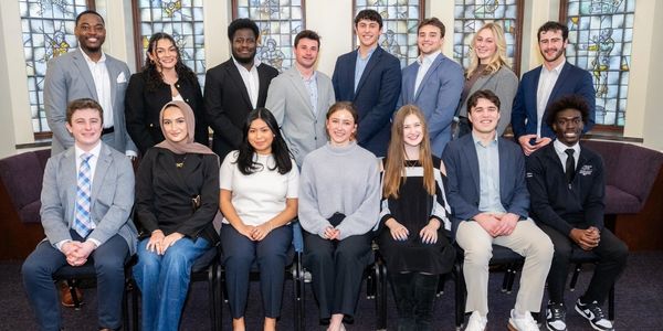 A diverse group of young adults posing formally indoors.