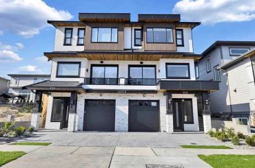 Modern duplex house with two garages and black accents.