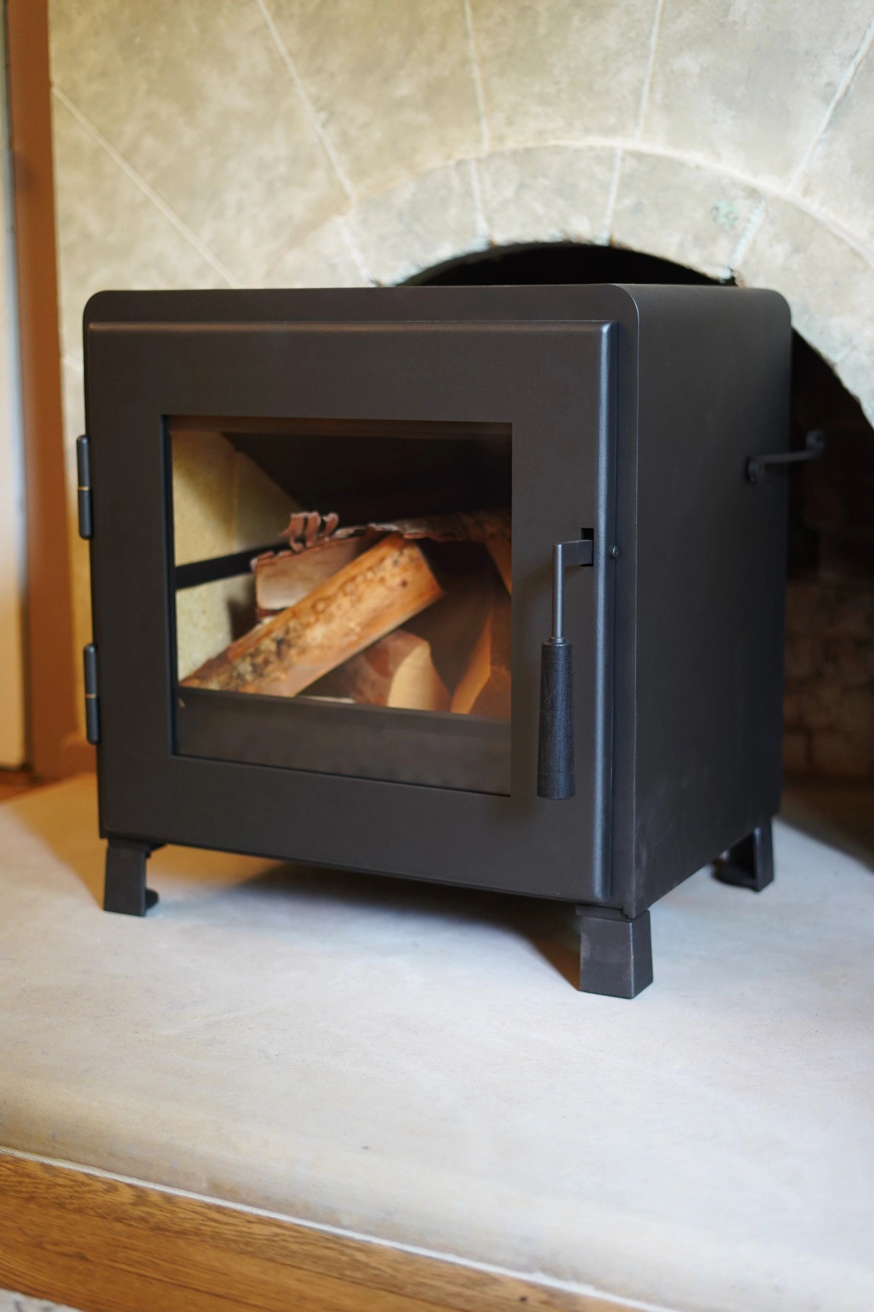 Modern black wood stove with logs inside.