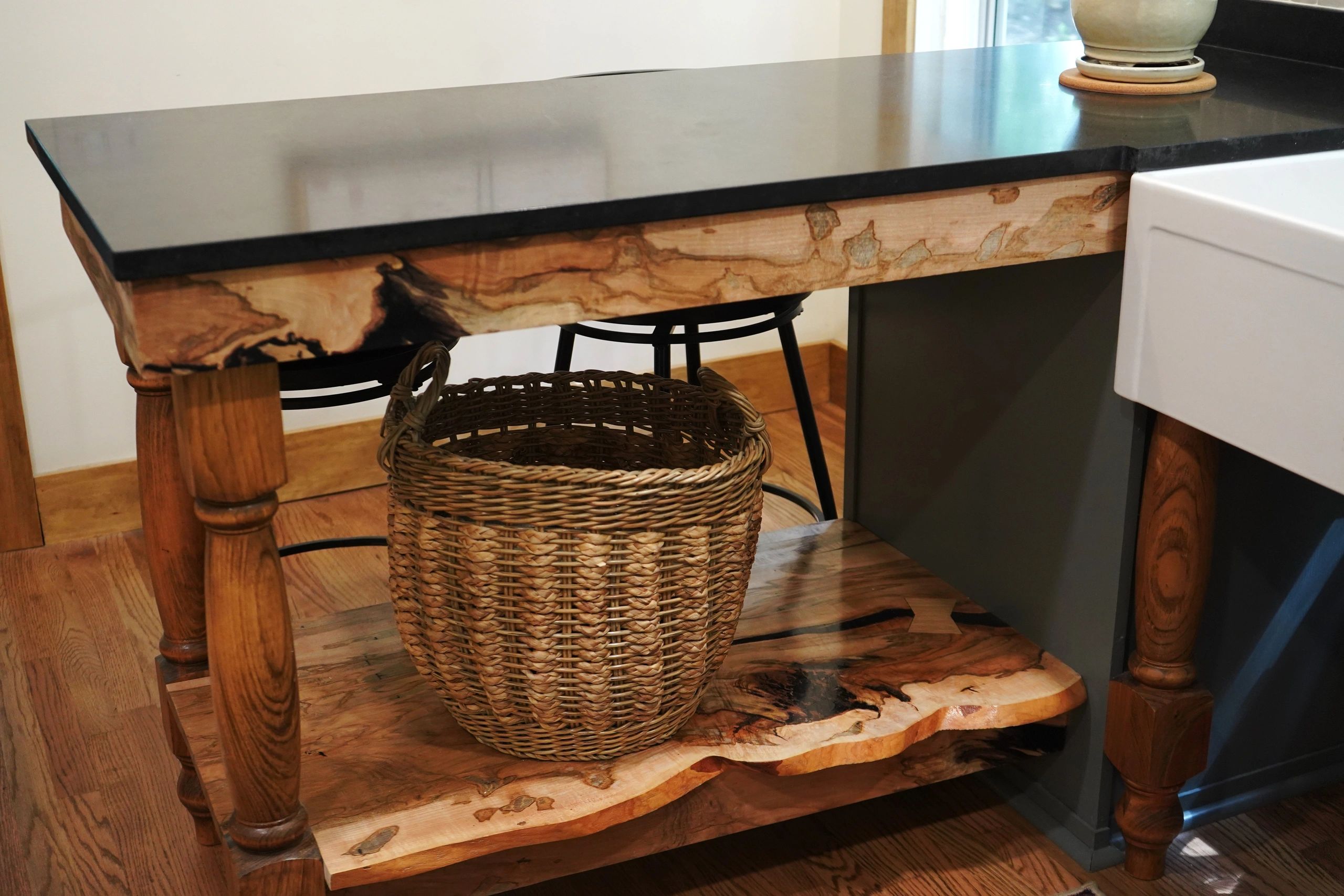 Wooden kitchen island with a woven basket underneath.