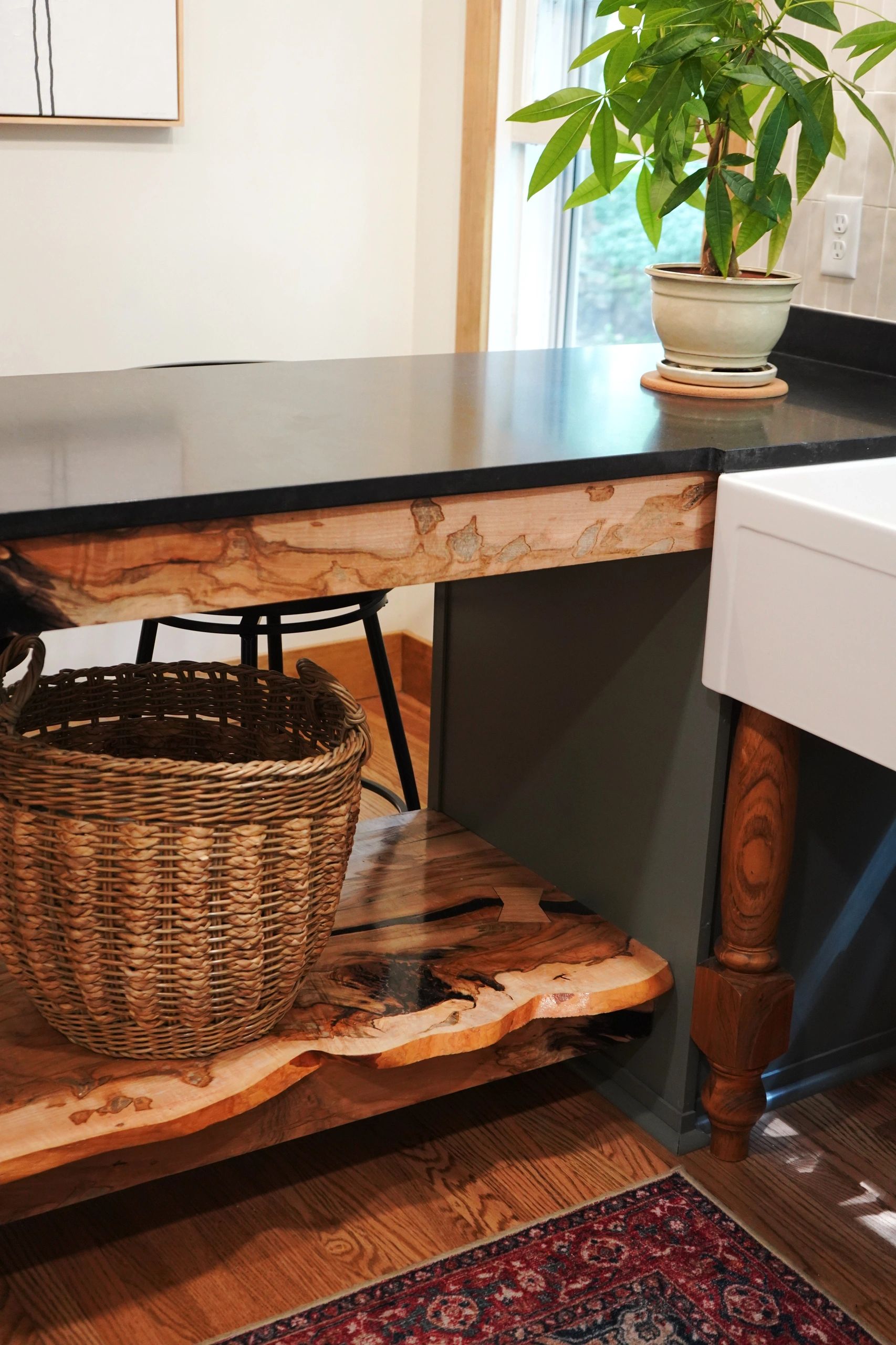 A kitchen corner with a plant, countertop, and basket.