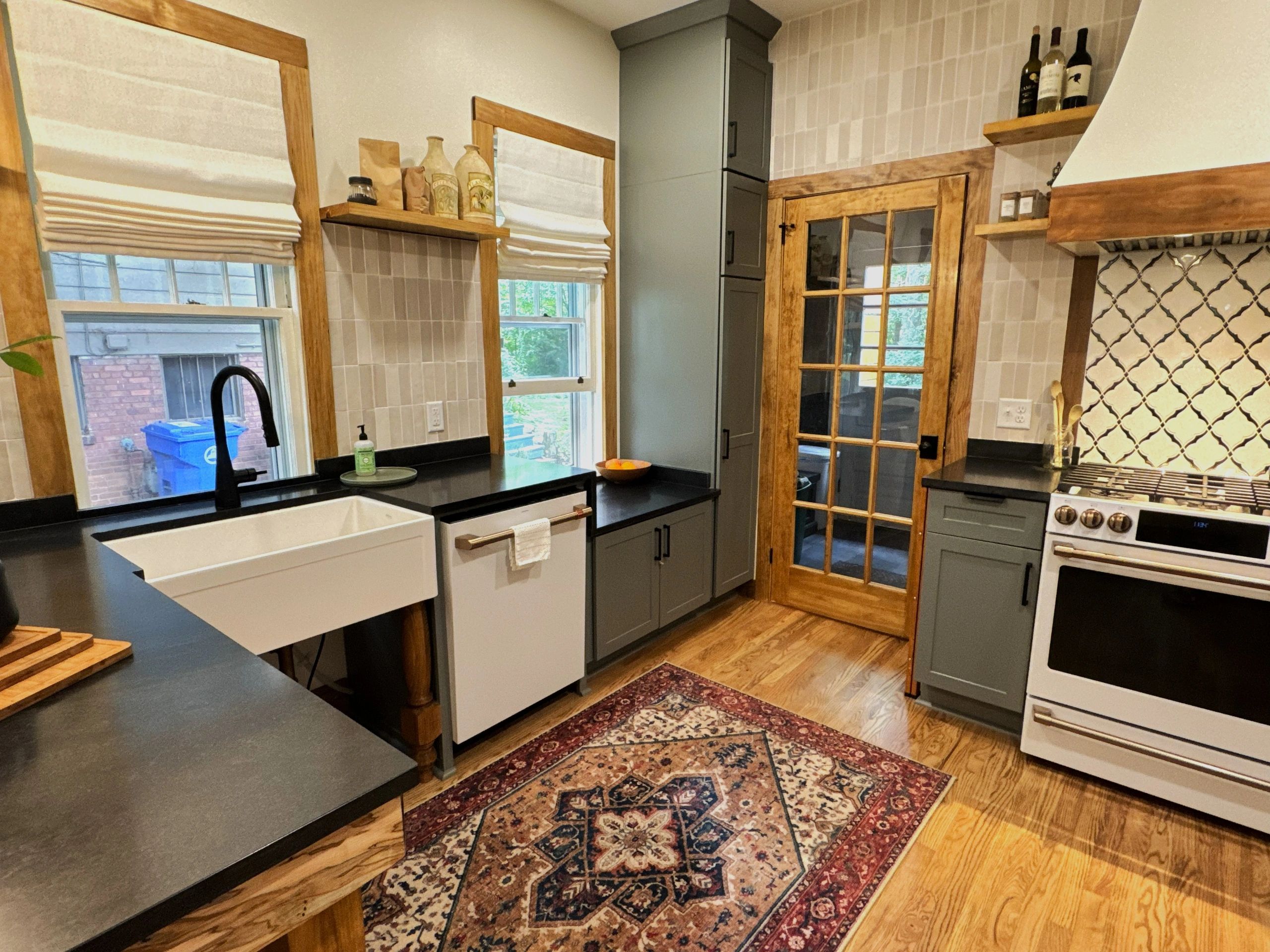 Cozy kitchen with gray cabinets, wooden trim, and patterned rug.