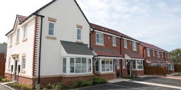 Row of modern suburban houses with parking spaces in front.