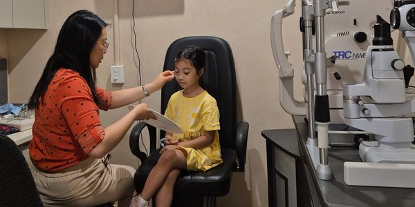 happy child being tested by optometrist in clinic