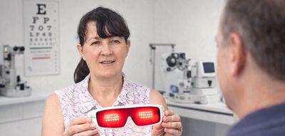 Woman showing red light therapy goggles to a man in an eye clinic.