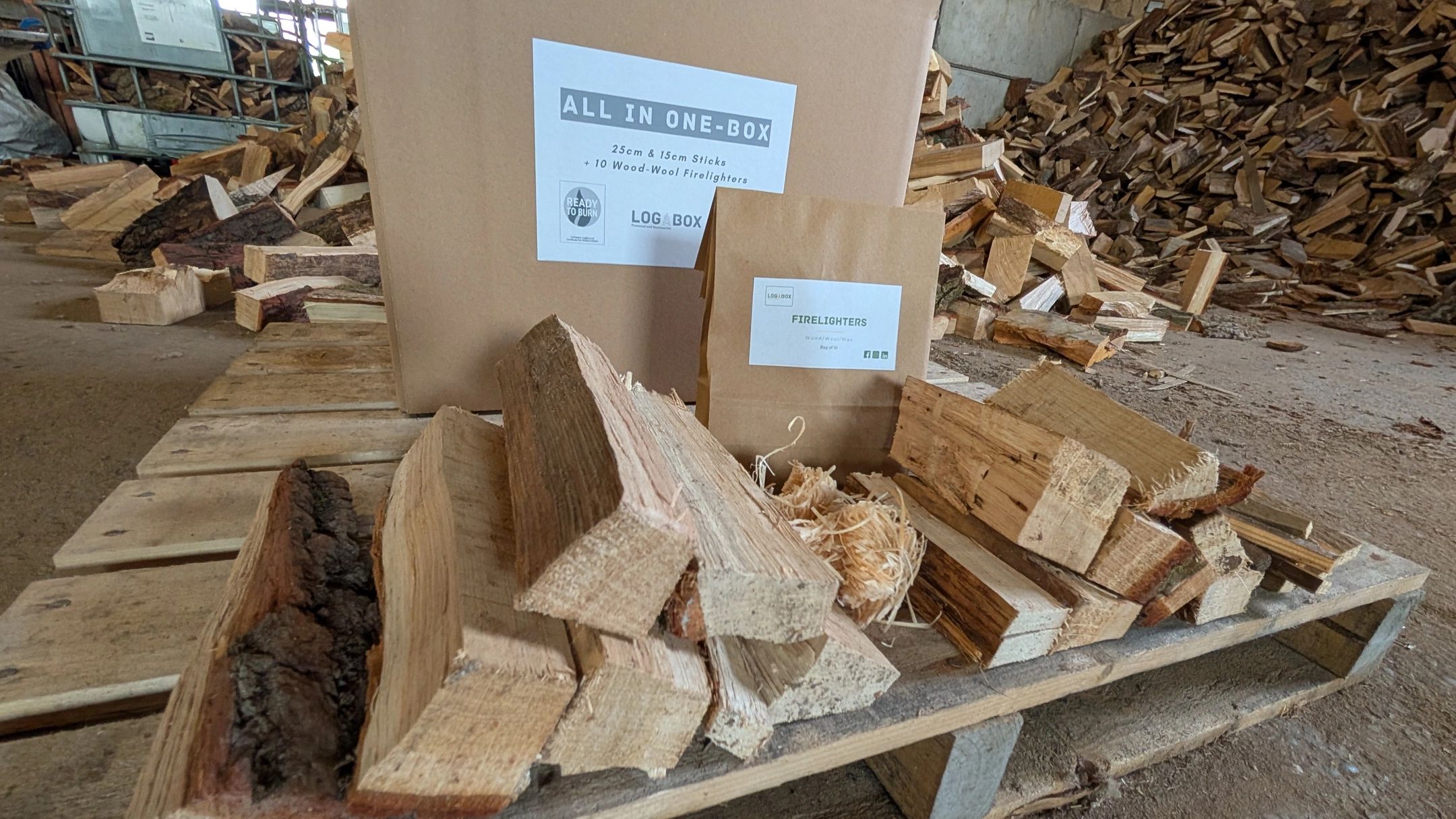 Stacked firewood and firelighters on a wooden pallet in a storage area.