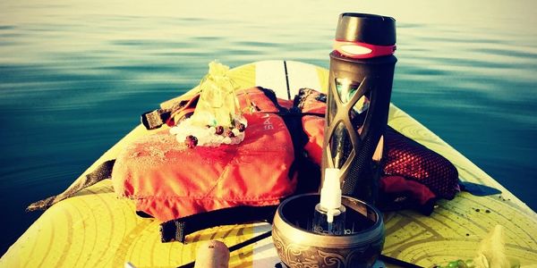Items on a paddleboard floating on calm water during sunset.