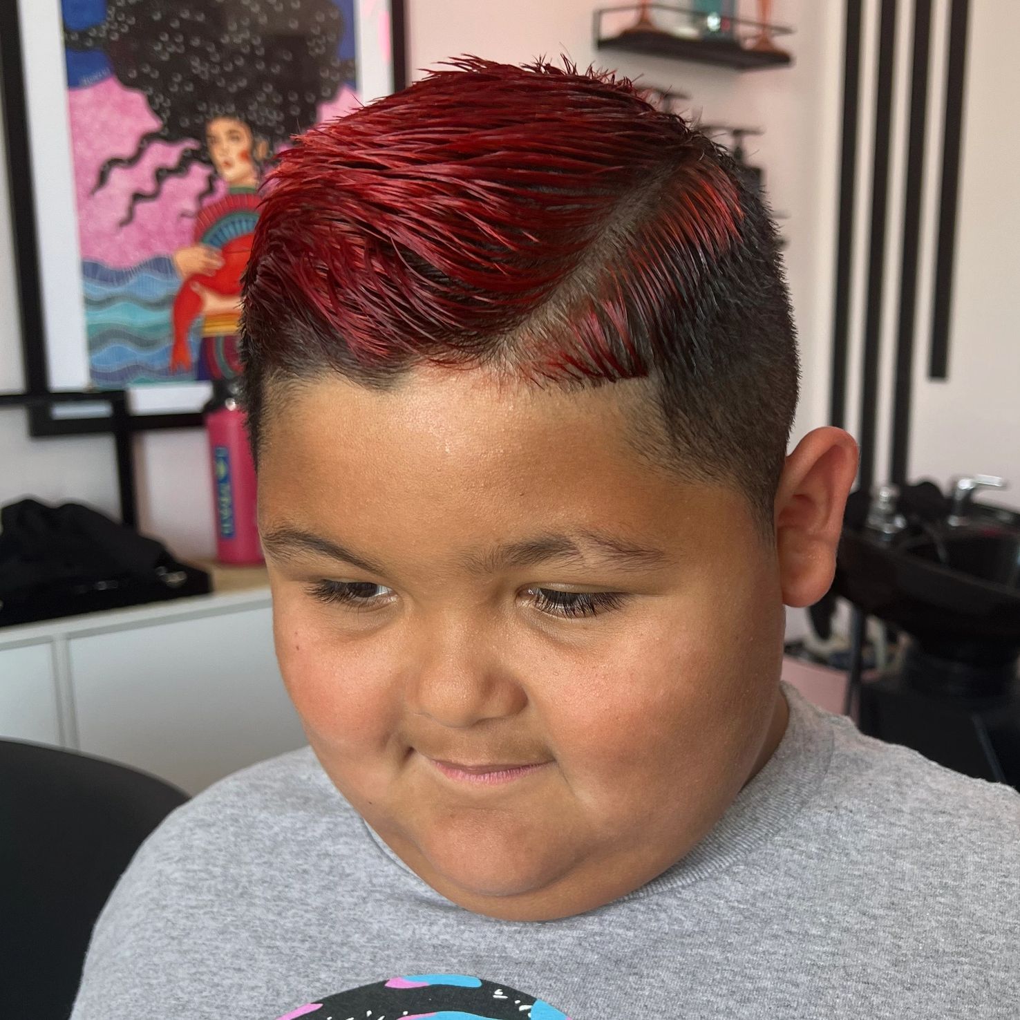 Boy with freshly dyed red hair looking down.