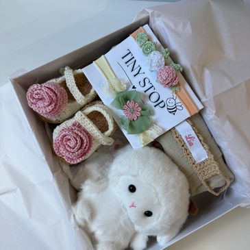 Gift box with crocheted baby shoes and a plush toy.