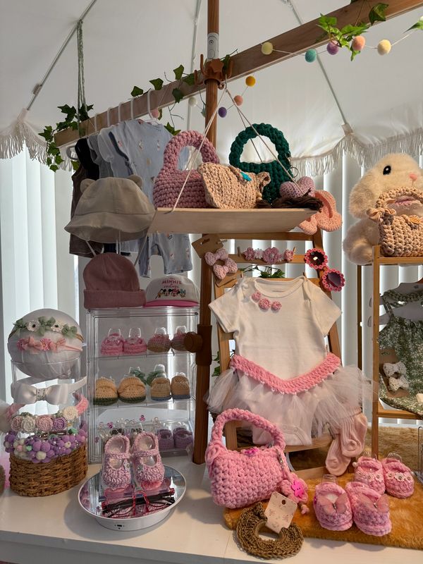 A display of baby clothes and knitted accessories.