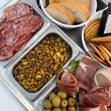 A charcuterie spread with meats, nuts, olives, and crackers.