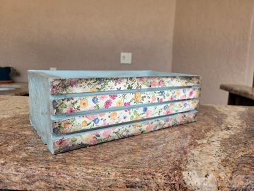 Decorative floral storage box with drawers.