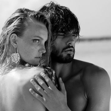 Intimate black and white portrait of a couple embracing at the beach.
