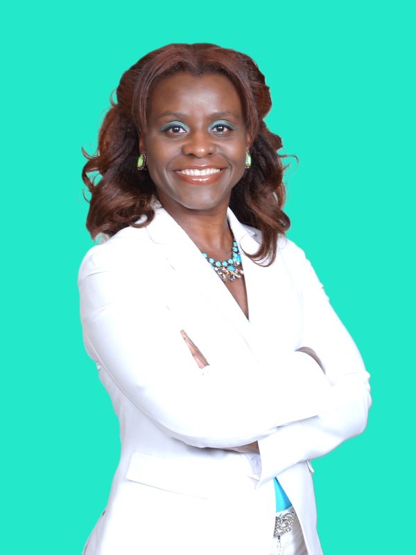 Confident woman in white suit smiling against teal background.