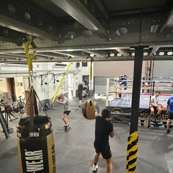 Boxing gym with people training and punching bags.