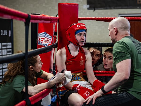 Young boxer receives coaching in the corner of the ring.