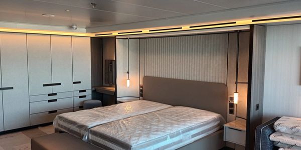 Modern bedroom with twin beds wrapped in plastic and built-in wardrobes.