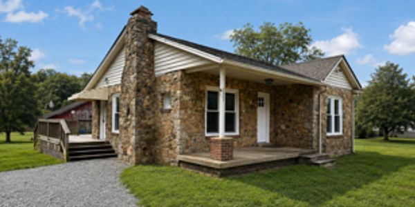 Stone house with a porch and gravel driveway.