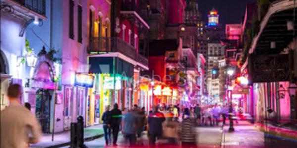 Vibrant city street at night with colorful lights and people walking.