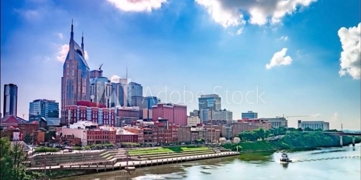 City skyline with river and boat under blue sky.