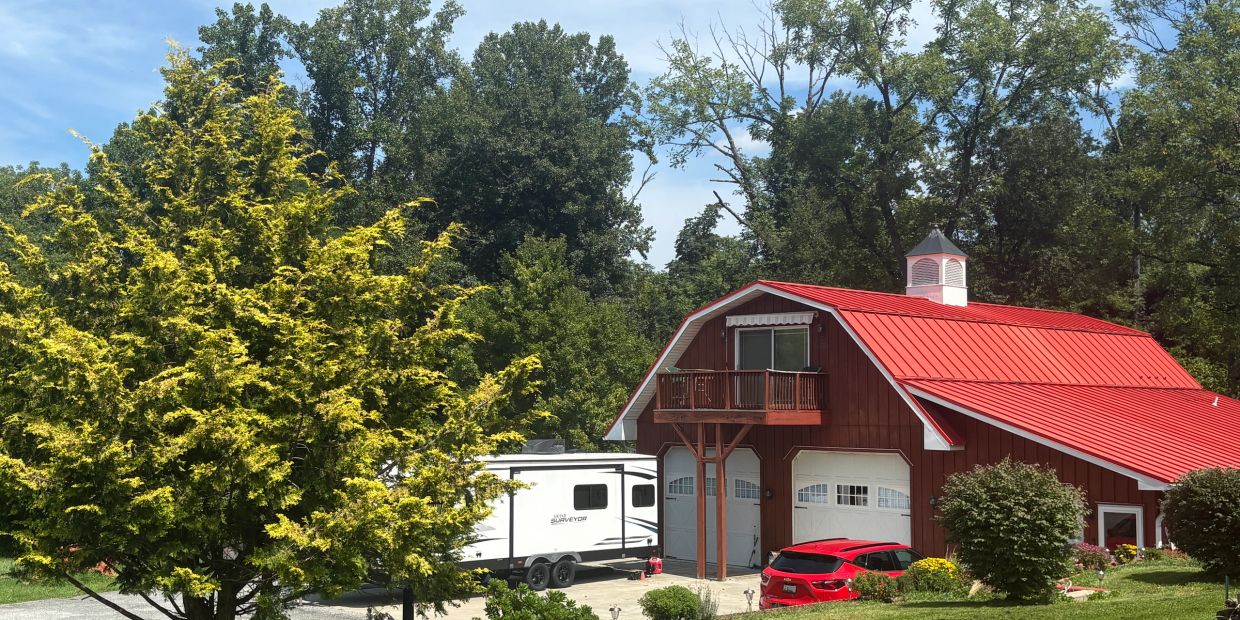Red barn-style garage with a red car and camper trailer.