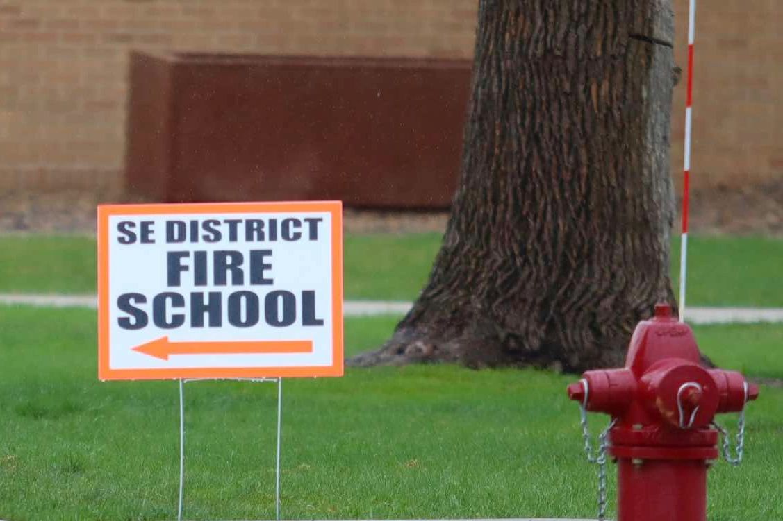 Sign pointing to SE District Fire School with fire hydrant nearby.