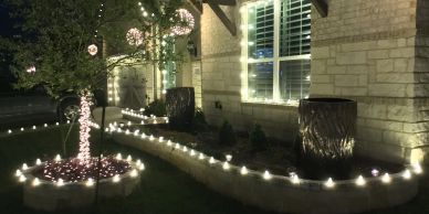 House exterior decorated with string lights and candles at night.