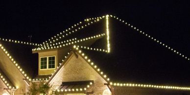 House roof outlined with warm white string lights at night.