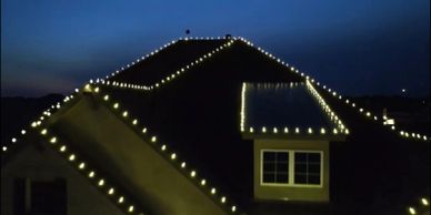 House roof decorated with string lights at dusk.