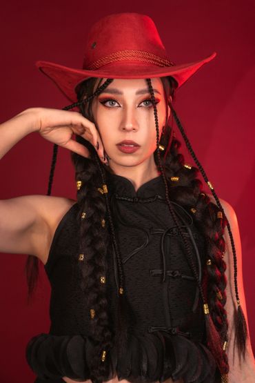 Woman in a red hat with long braided hair and black outfit.
