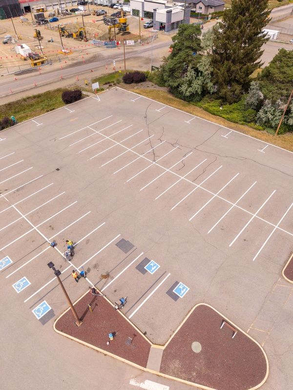 Empty parking lot with a few people near handicap spaces.