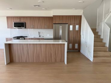 Modern kitchen with wooden cabinets, white countertops, and stainless steel appliances.