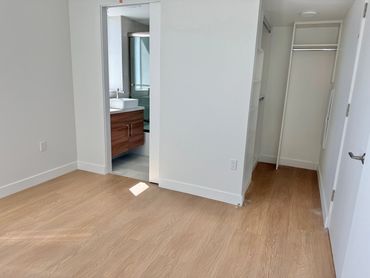 Empty room with wood flooring, closet, and bathroom entrance.