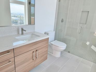 Modern bathroom with wooden vanity, toilet, and glass shower enclosure.