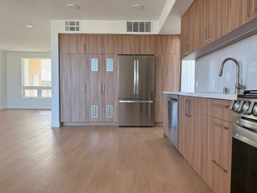 Modern kitchen with stainless steel appliances and wood cabinetry in a bright open space.