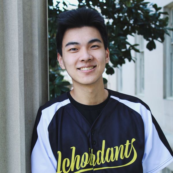 Young man smiling outdoors wearing a black and white sports jersey.