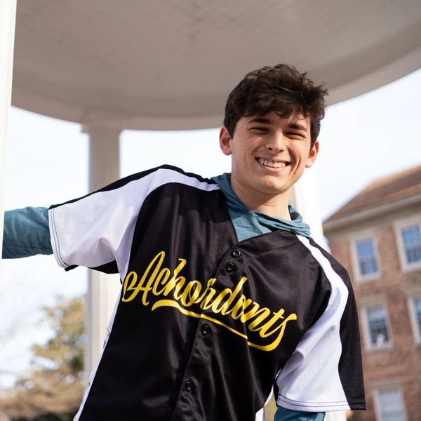 Smiling young man wearing a black and white jersey outdoors.