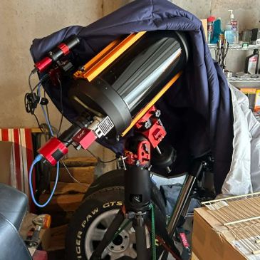 Large telescope covered partially by a jacket in a garage setting.