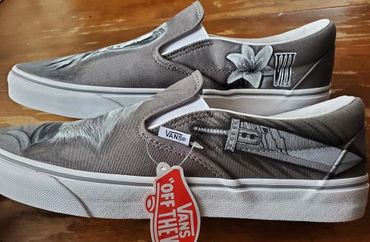 Custom Vans slip-ons with intricate black and white designs on grey canvas.