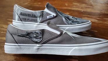 Custom Vans slip-on shoes with space-themed artwork and text.