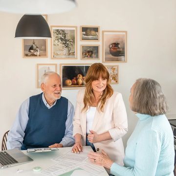 Three adults discussing paperwork in a cozy office setting.
