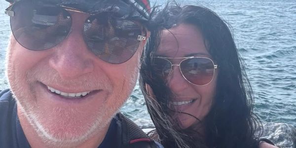 A smiling couple with sunglasses by the water.